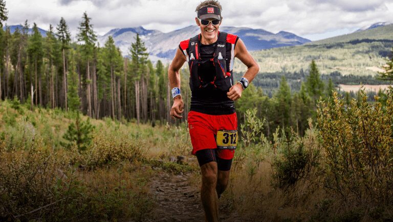 A man running in the woods wearing red shorts.